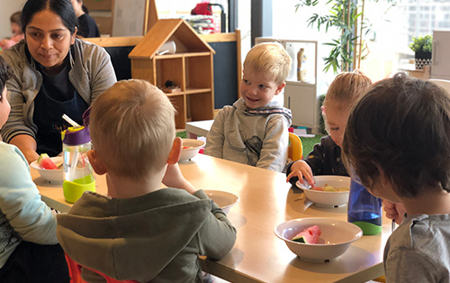 Children at Preschool sitting around table eating fruit