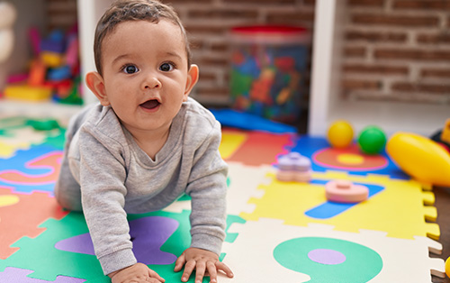 Adorable baby crawling on floor at kindergarten